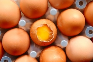 Tray of eggs with one broken egg visible