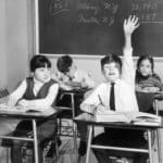 keen pupil raising arm to give answer in class
